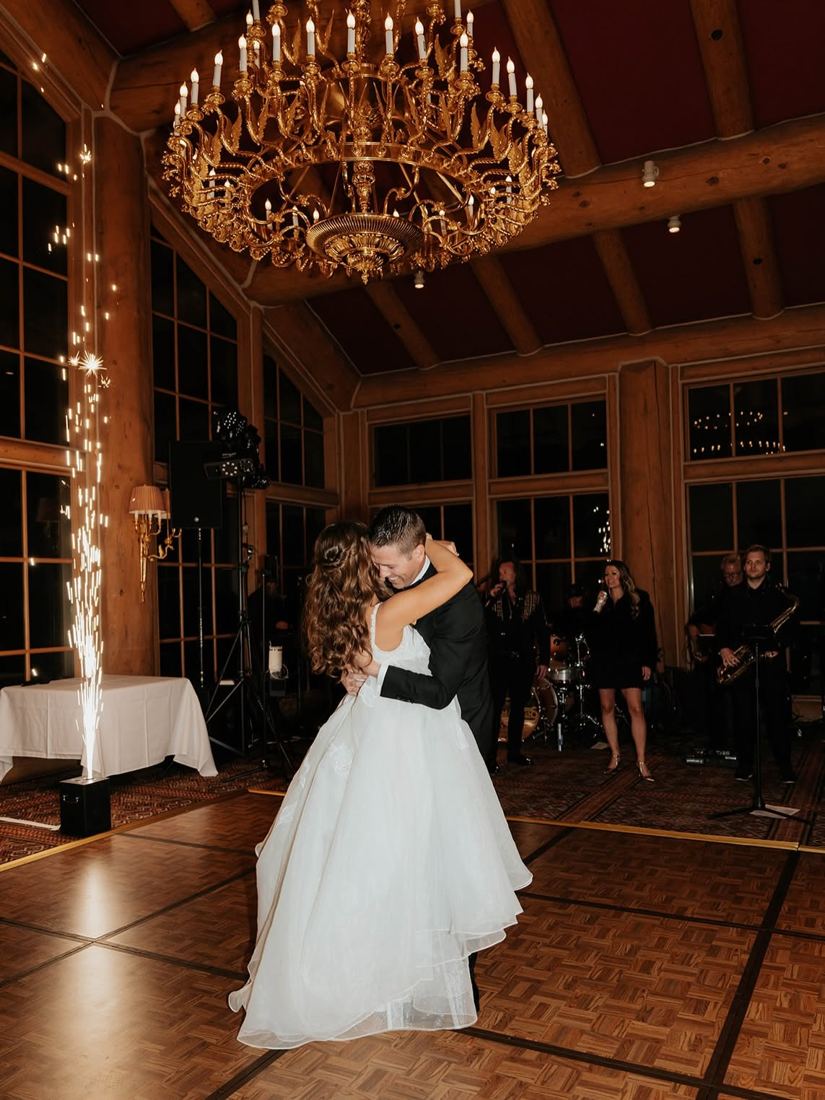 Bride with long brunette waves during her first dance under a chandelier